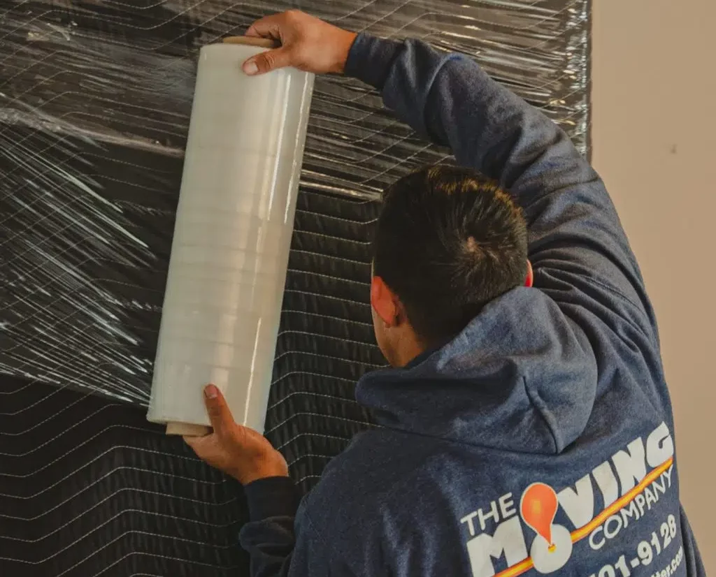 the moving company team member plastic wrapping furniture