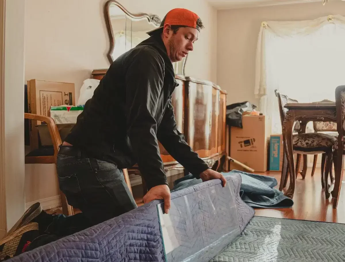 the moving company team member wrapping furniture with packing blanket