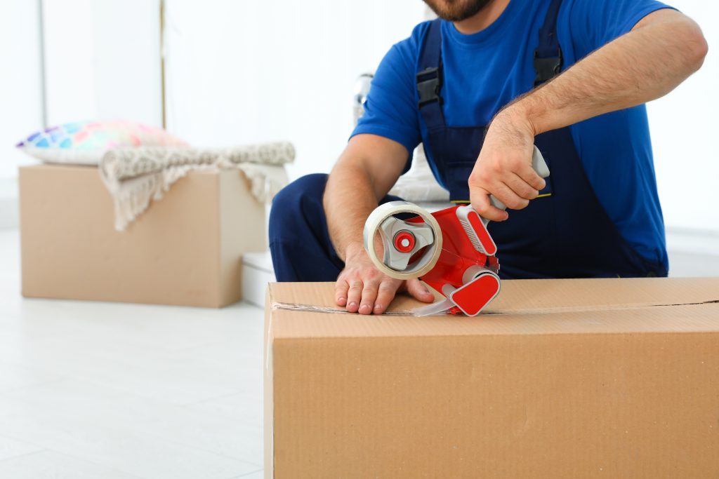 Moving employee sealing a box with packaging tape